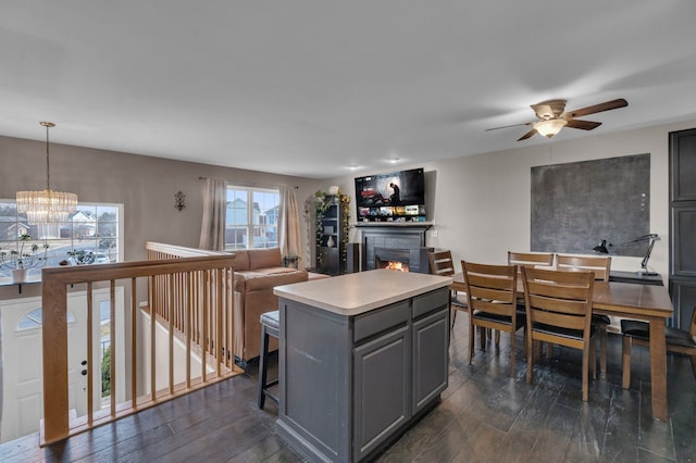 kitchen featuring dark wood-style floors, a kitchen island, a lit fireplace, light countertops, and gray cabinetry