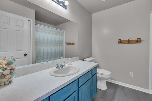 bathroom with baseboards, toilet, wood finished floors, curtained shower, and vanity