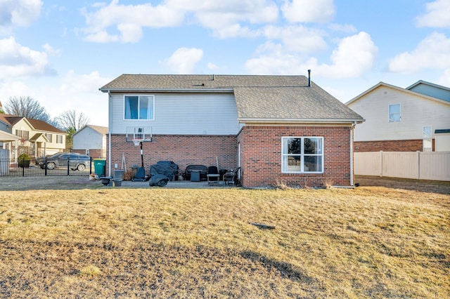 rear view of house featuring brick siding, a yard, and fence