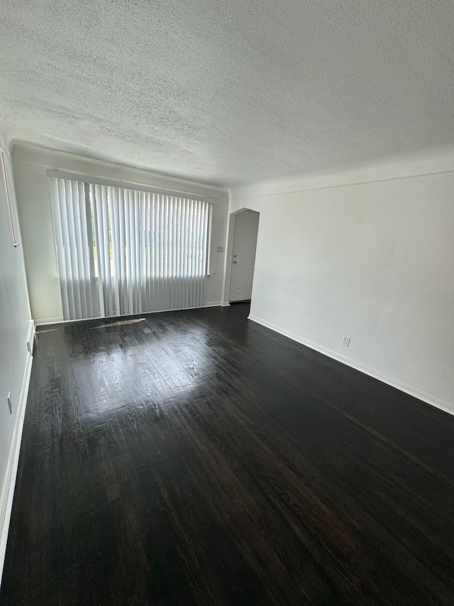 spare room featuring dark wood-style floors, baseboards, and a textured ceiling