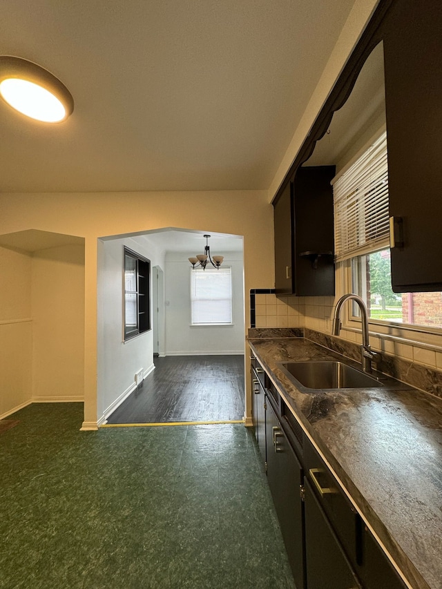 14919 Fairmount Dr, Detroit, MI 48205 - kitchen featuring a notable chandelier, dark countertops, decorative backsplash, a sink, and baseboards