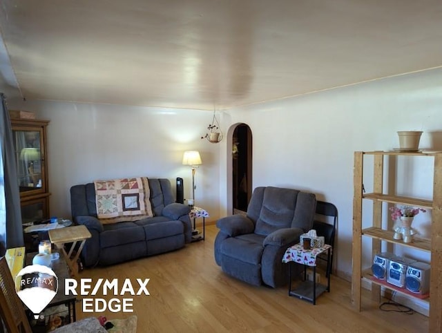 living area with arched walkways and wood finished floors