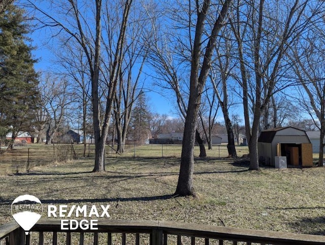 view of yard featuring a shed, fence, and an outbuilding