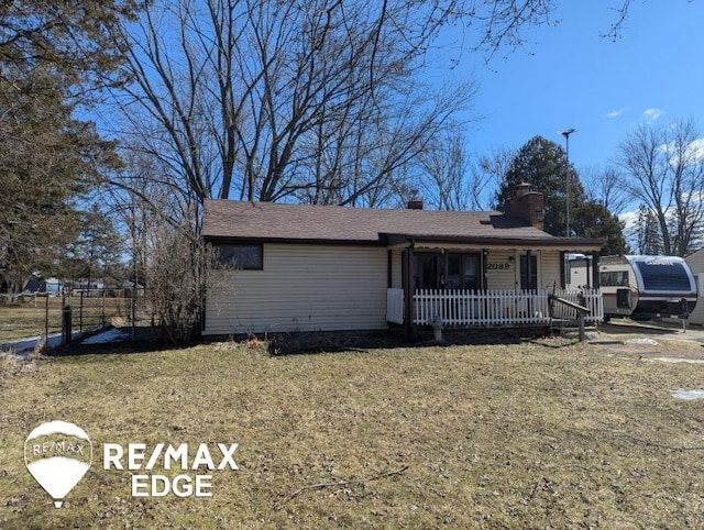 ranch-style home featuring covered porch, fence, a chimney, and a front lawn