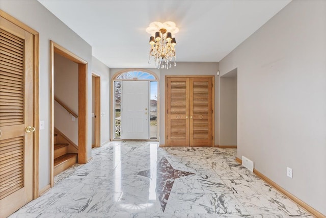 entrance foyer with marble finish floor, a notable chandelier, visible vents, stairway, and baseboards