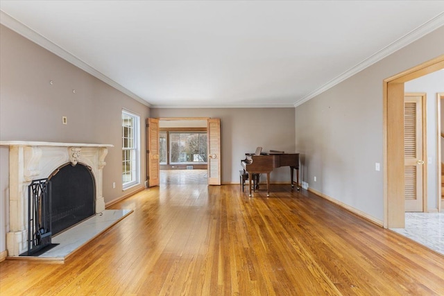 unfurnished living room with light wood-style flooring, ornamental molding, a fireplace with raised hearth, and baseboards