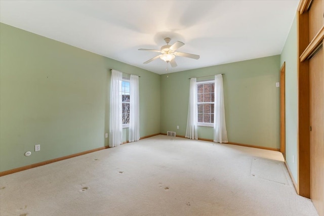 spare room featuring light colored carpet, a healthy amount of sunlight, visible vents, and baseboards