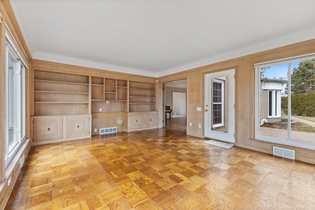 unfurnished living room featuring visible vents and built in study area