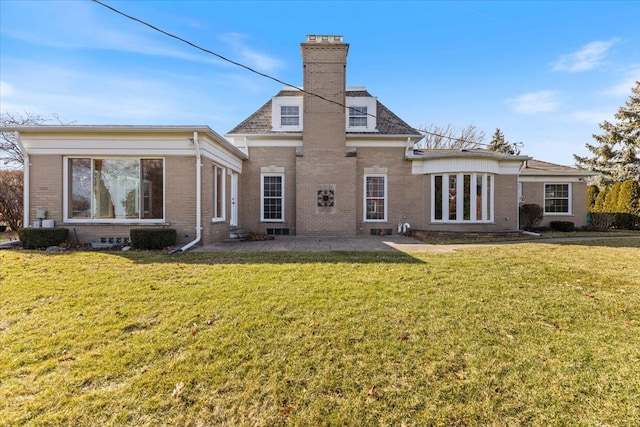 rear view of house featuring a chimney, a lawn, and brick siding