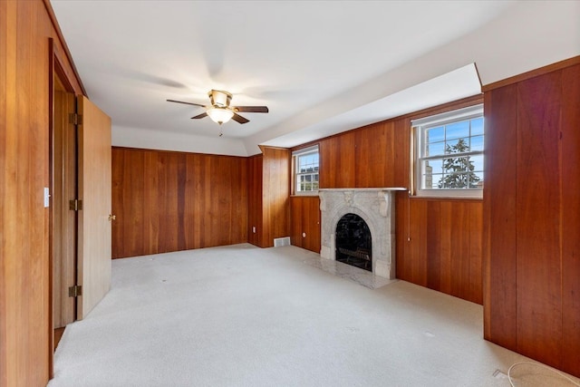 living room featuring visible vents, wood walls, a high end fireplace, and light colored carpet