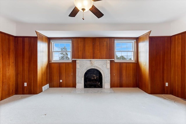 unfurnished living room with a wealth of natural light, visible vents, a fireplace, and wooden walls