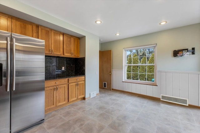 kitchen featuring brown cabinets, visible vents, stainless steel refrigerator with ice dispenser, and wainscoting