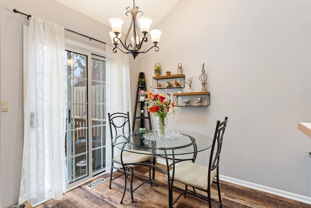 dining space with visible vents, an inviting chandelier, vaulted ceiling, wood finished floors, and baseboards