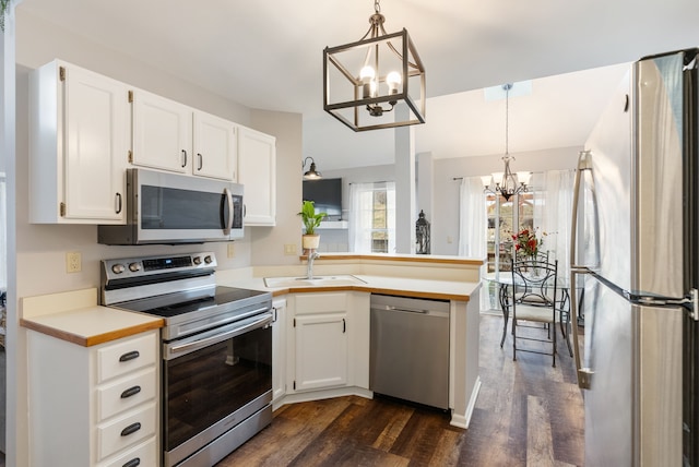 kitchen featuring a notable chandelier, stainless steel appliances, a sink, white cabinets, and light countertops