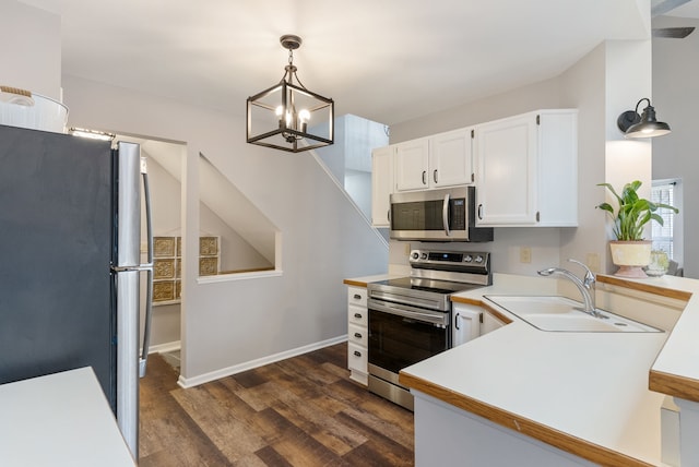 kitchen with white cabinets, dark wood-style floors, stainless steel appliances, light countertops, and a sink