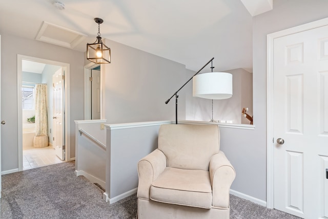 sitting room featuring attic access, baseboards, carpet flooring, and an upstairs landing