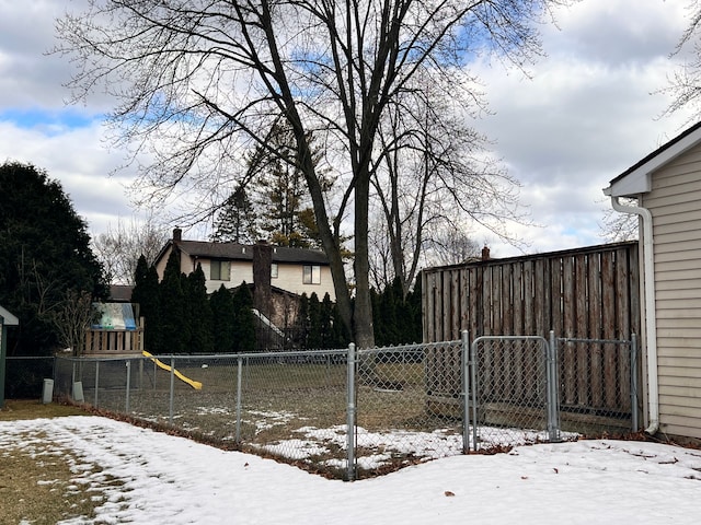 snowy yard featuring a playground and fence