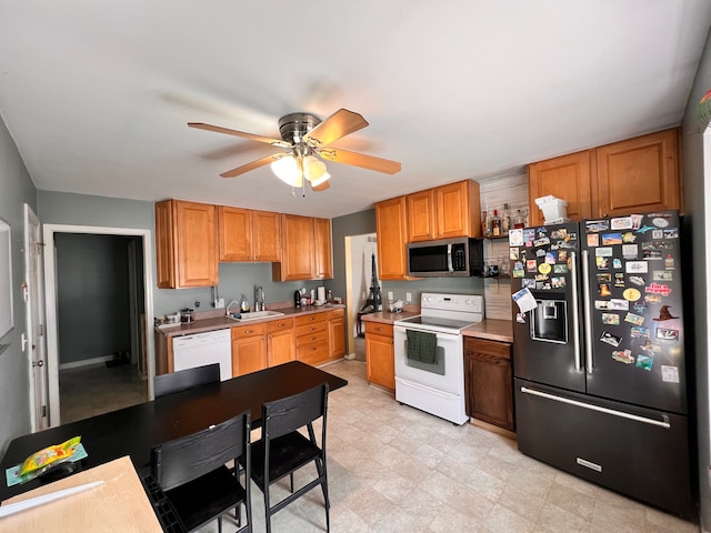 kitchen featuring light floors, light countertops, a sink, ceiling fan, and white appliances