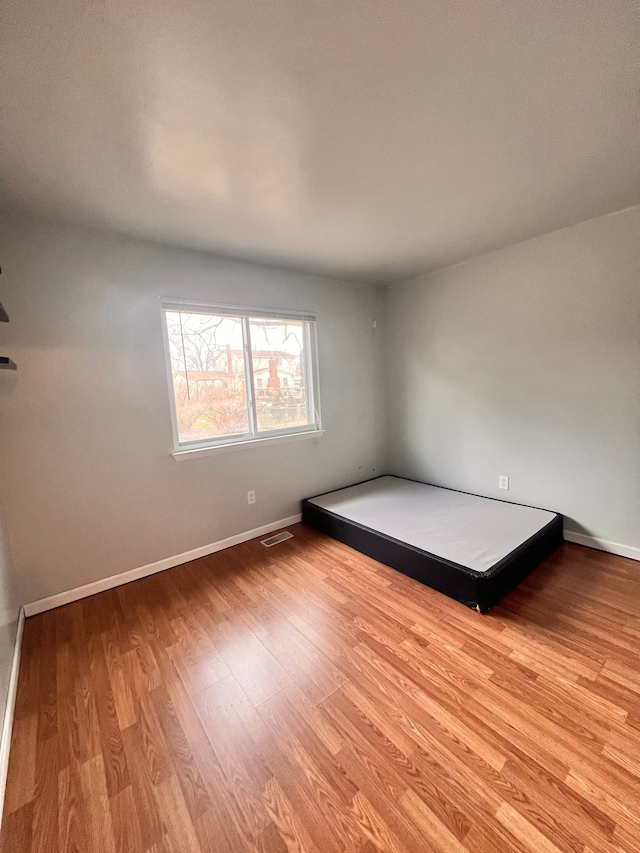 unfurnished bedroom with baseboards, visible vents, and wood finished floors