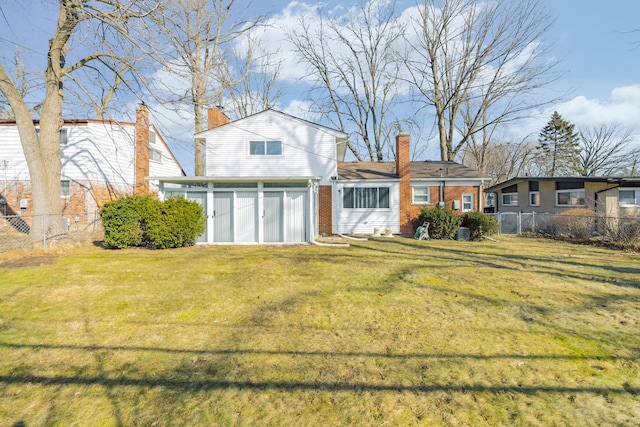 rear view of property with a yard, brick siding, a chimney, and fence