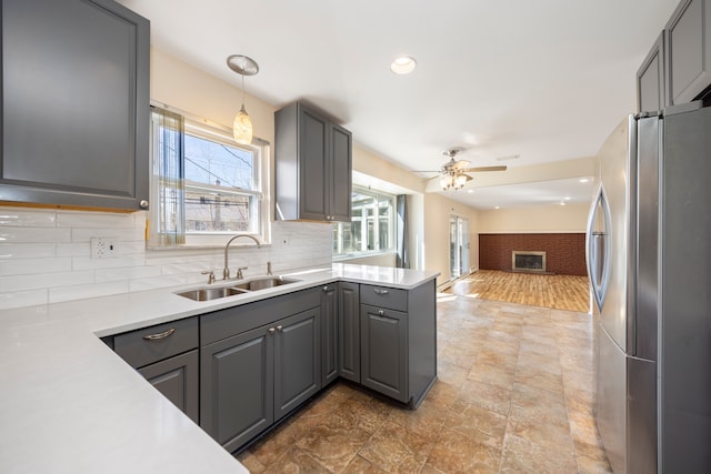 kitchen with gray cabinets, a sink, tasteful backsplash, open floor plan, and freestanding refrigerator