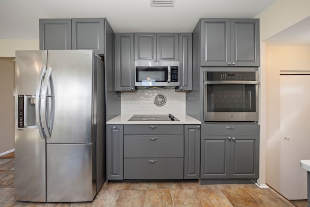 kitchen with tasteful backsplash, baseboards, light countertops, gray cabinets, and stainless steel appliances