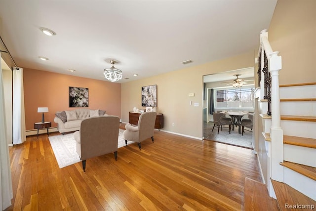 living room with stairway, baseboards, visible vents, a baseboard radiator, and hardwood / wood-style flooring