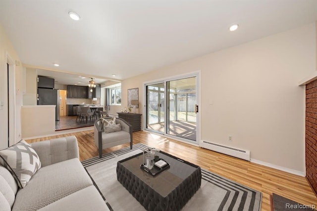 living room featuring a brick fireplace, baseboards, baseboard heating, recessed lighting, and light wood-style floors