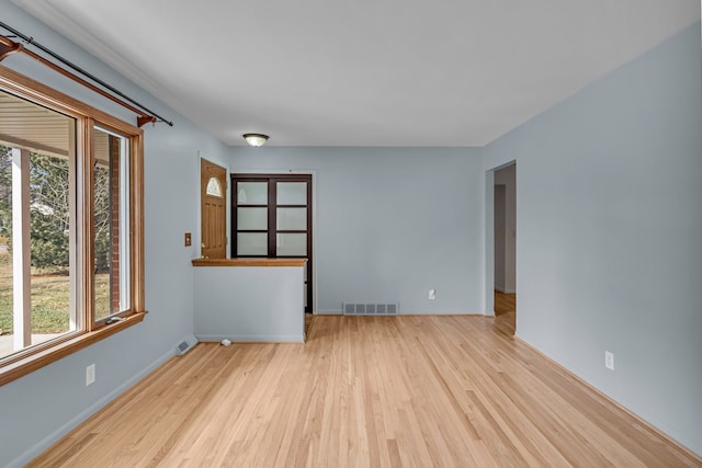 spare room featuring visible vents, baseboards, and wood finished floors