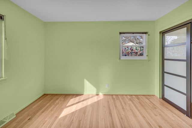 spare room with visible vents, baseboards, and wood finished floors