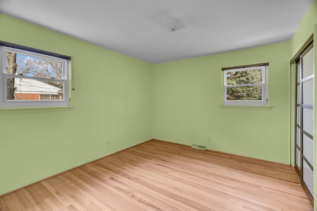 unfurnished bedroom featuring light wood-style flooring, multiple windows, visible vents, and baseboards