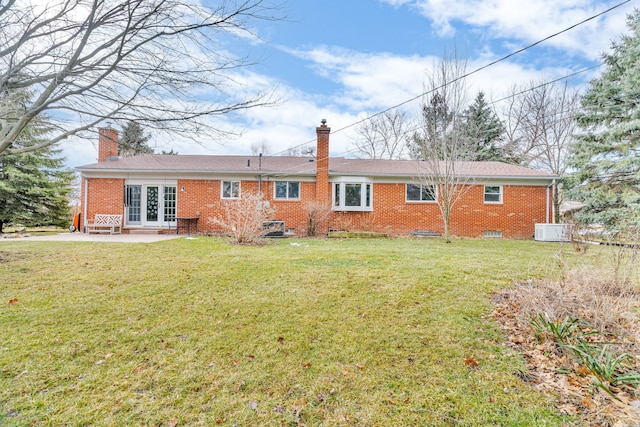 back of property featuring central AC unit, brick siding, a lawn, a chimney, and a patio area