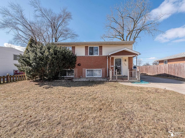 view of front of home with a front yard, brick siding, and fence