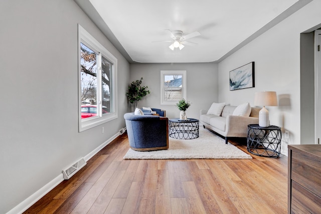 living room featuring hardwood / wood-style floors, a ceiling fan, visible vents, and baseboards