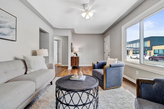 living room with a ceiling fan, baseboards, and wood finished floors