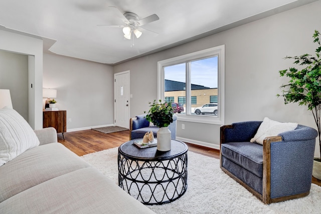 living area with ceiling fan, baseboards, and wood finished floors