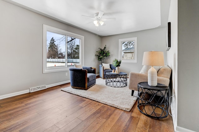 sitting room featuring a ceiling fan, baseboards, visible vents, and hardwood / wood-style floors