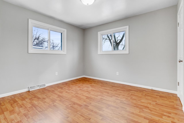 unfurnished room featuring baseboards, visible vents, and light wood finished floors