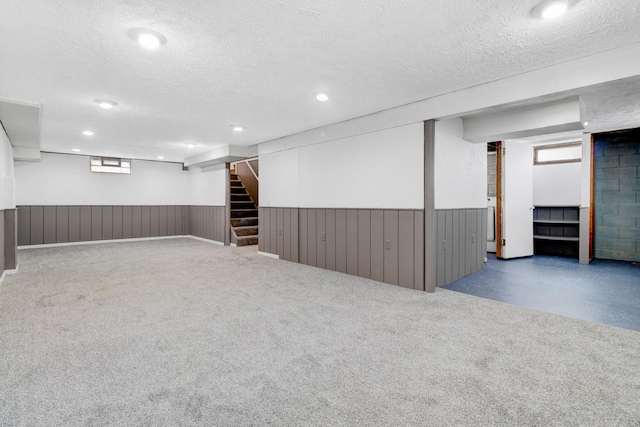 basement with a wainscoted wall, stairway, a textured ceiling, and recessed lighting