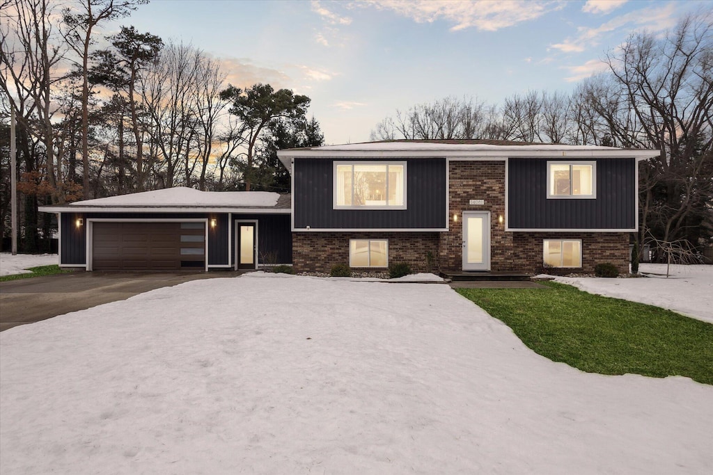 split foyer home featuring a garage, driveway, and brick siding