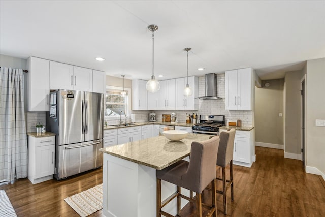 kitchen with dark wood-style floors, decorative backsplash, appliances with stainless steel finishes, a sink, and wall chimney range hood