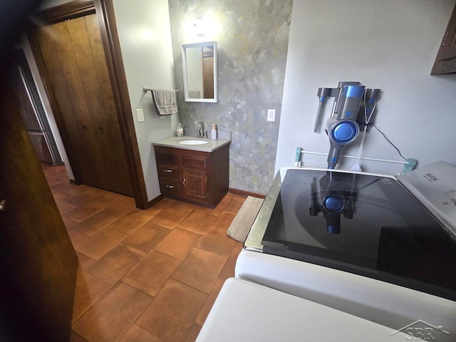 bathroom featuring vanity, baseboards, and wallpapered walls