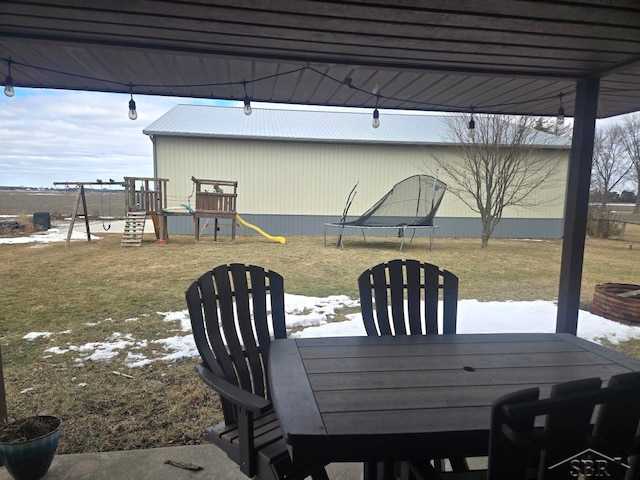 view of patio / terrace with a trampoline, outdoor dining area, and a playground