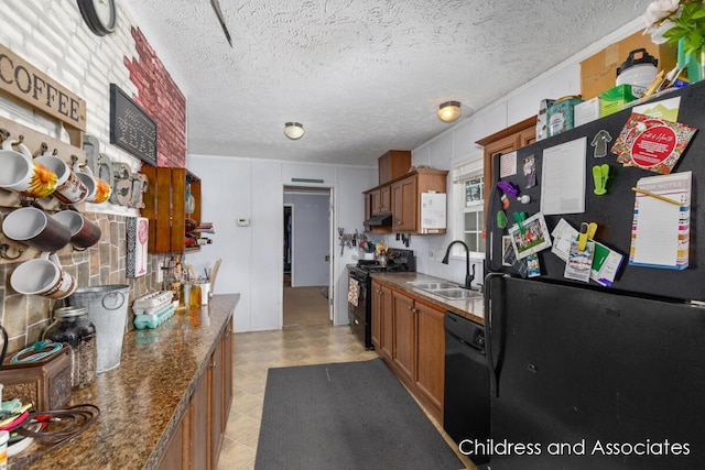 kitchen with black appliances, dark countertops, a sink, and brown cabinets