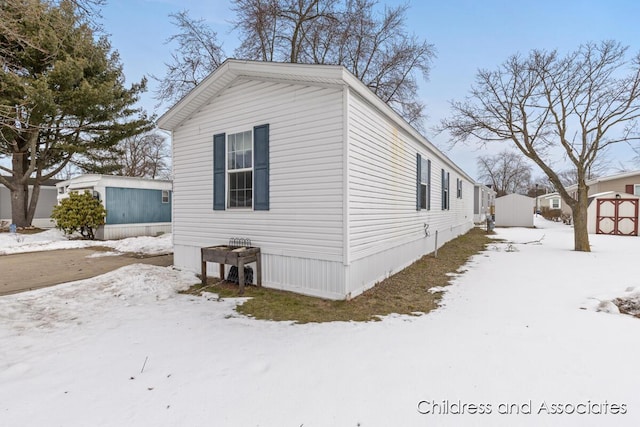 snow covered property with a storage shed and an outbuilding