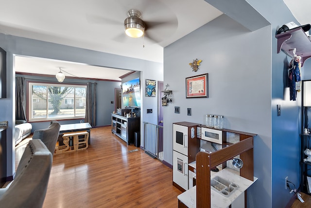 interior space with white microwave, a ceiling fan, and wood finished floors