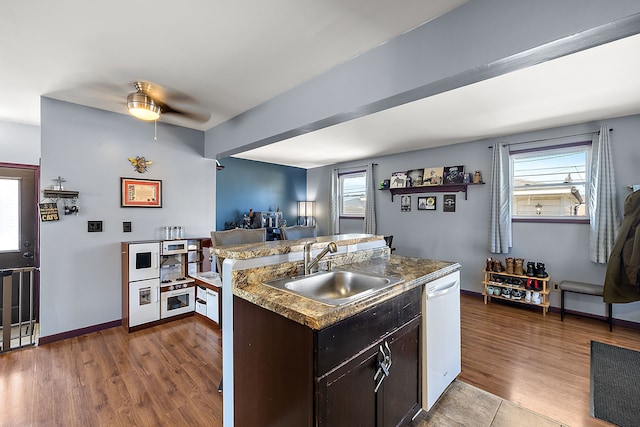 kitchen featuring dishwasher, plenty of natural light, a sink, and wood finished floors