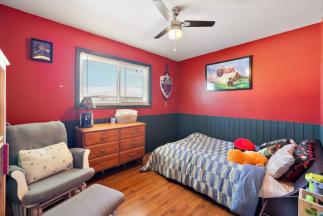 bedroom with a wainscoted wall, ceiling fan, and wood finished floors