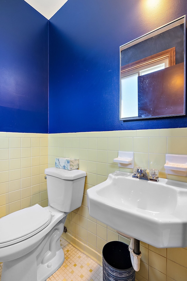 half bathroom featuring tile walls, toilet, and tile patterned floors