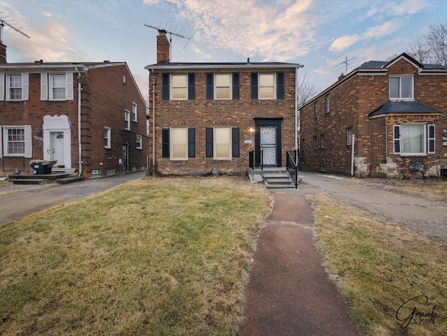 colonial inspired home featuring brick siding, a chimney, and a front lawn